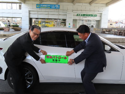 沼津信用金庫の方とと市長が車にステッカーを貼る様子
